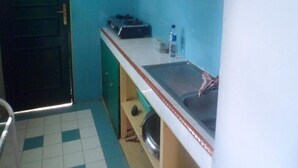 Een kleine keuken met een spoelbak, fornuis en waterdispenser.