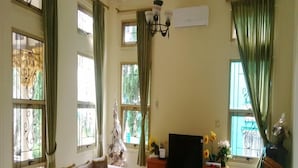 A living room with a sofa set, a television, and a decorative vase. - Kota Bunga CC (Cipanas)