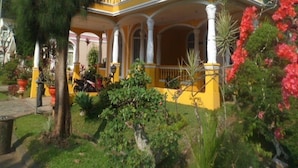 A yellow house with a balcony and a garden. - Kota Bunga CC (Cipanas)