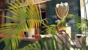 Un vestíbulo con mostrador de recepción, un emblema decorativo y plantas verdes exuberantes.