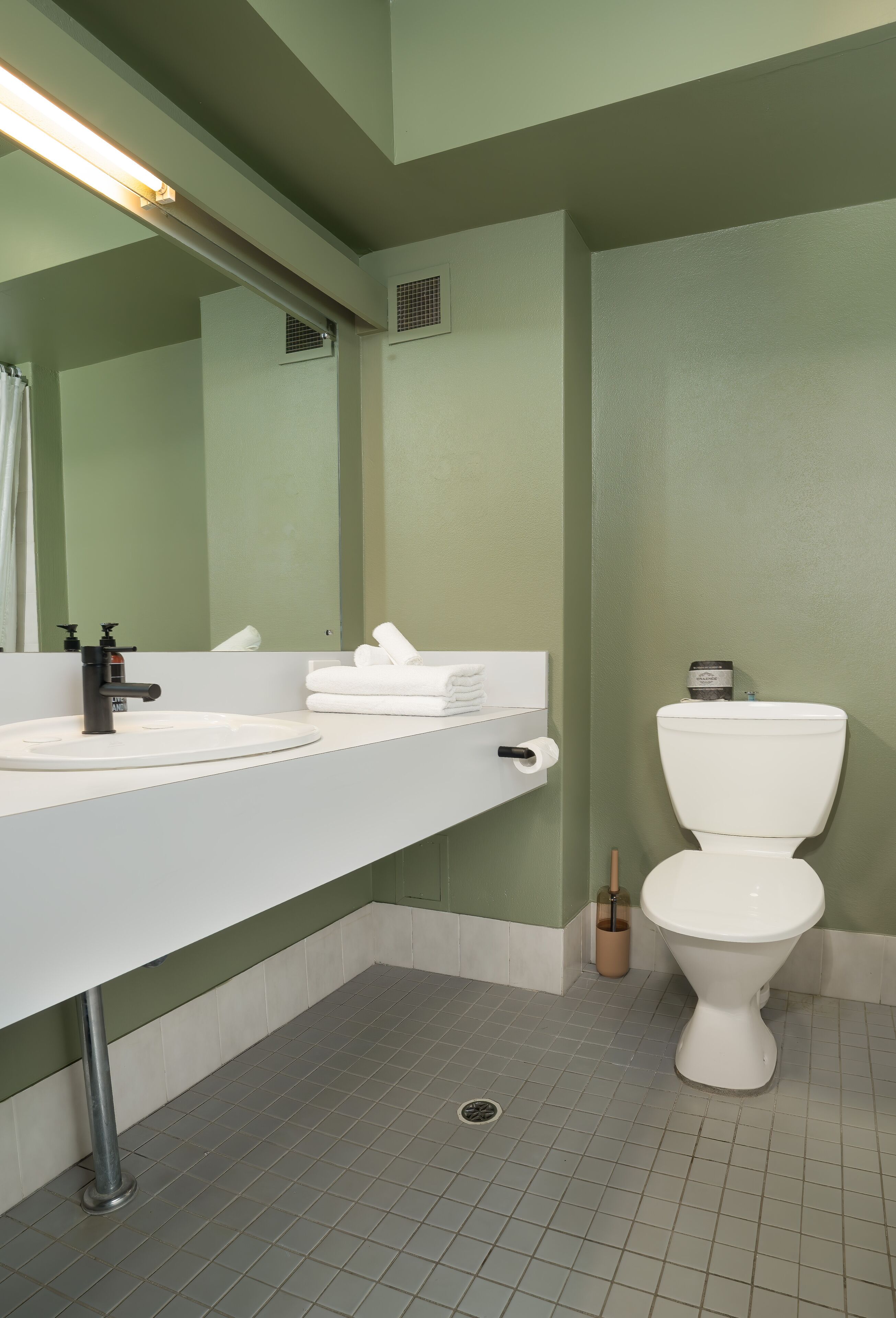 Een badkamer met een wit wastafel, een spiegel, een toilet en een douchegordijn.