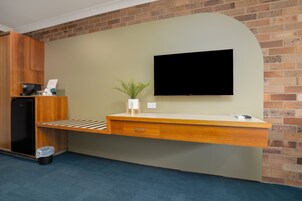 Una mesa de recepción con un televisor de pantalla plana, una planta en maceta y una máquina de café.