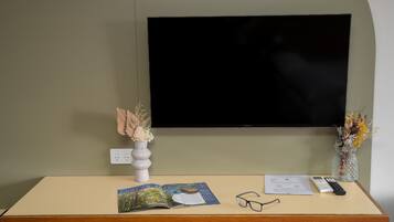 Een bureau met een tijdschrift, een bril, een afstandsbediening en twee vazen met gedroogde bloemen.