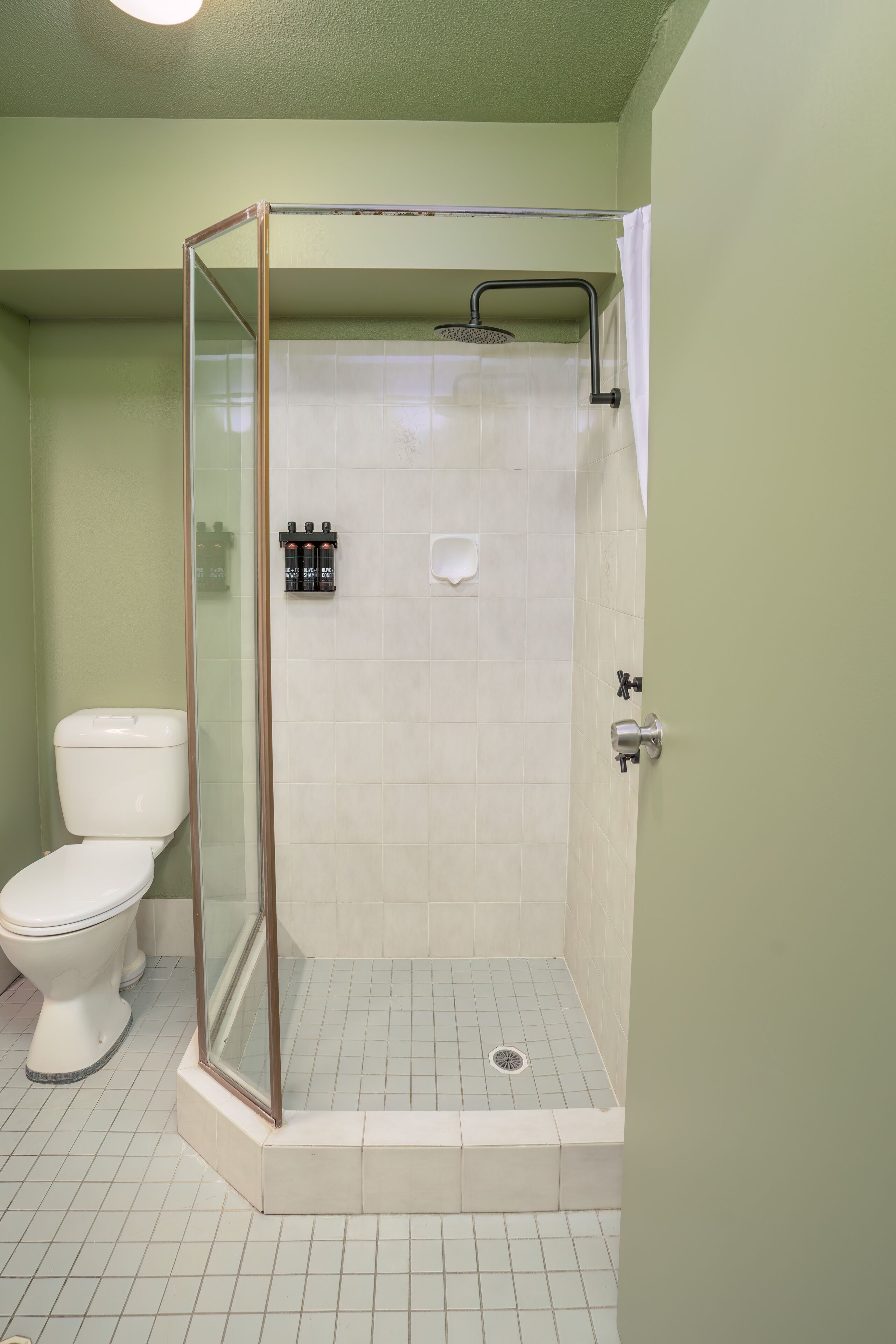 A bathroom with a glass-enclosed shower, a toilet, and a sink.