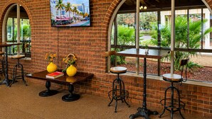 A restaurant with brick walls, arched windows, and a table with yellow vases and books. - All Seasons Motel Armidale (Armidale)
