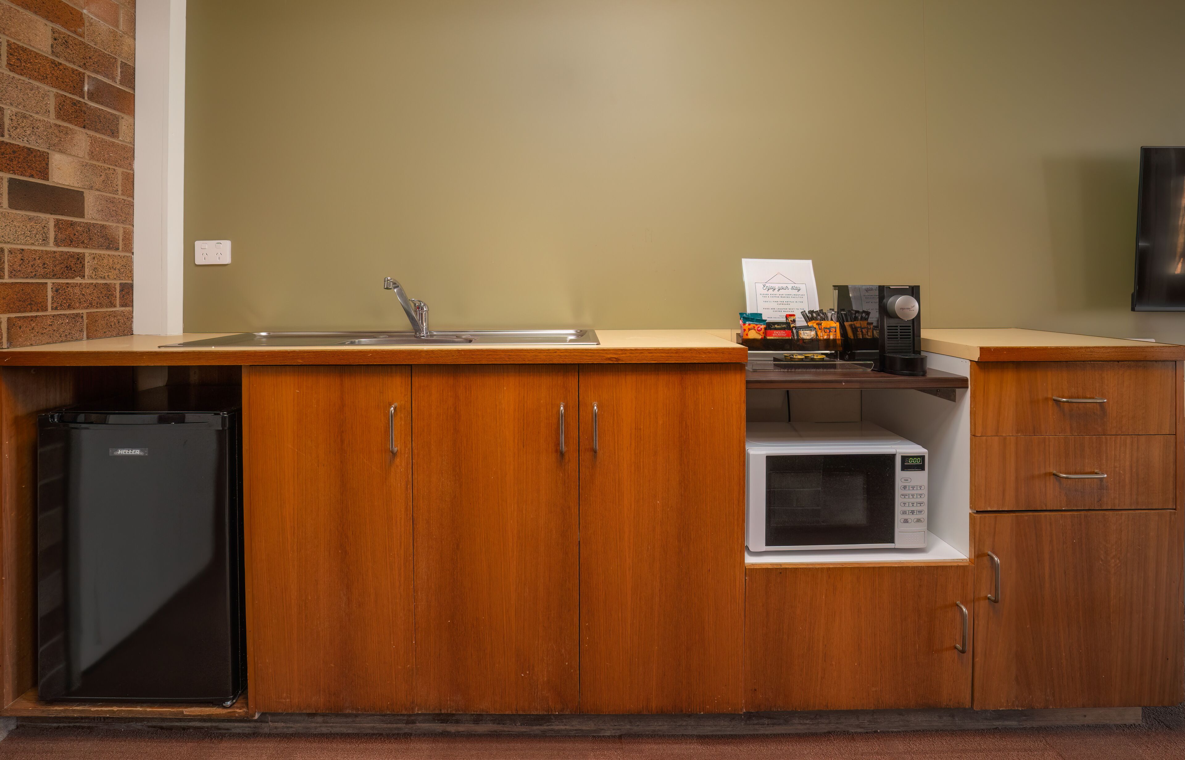 A compact kitchen with a sink, a microwave, and a refrigerator.