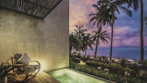 Un balcon avec vue sur l’océan, une chaise en osier et une petite piscine.