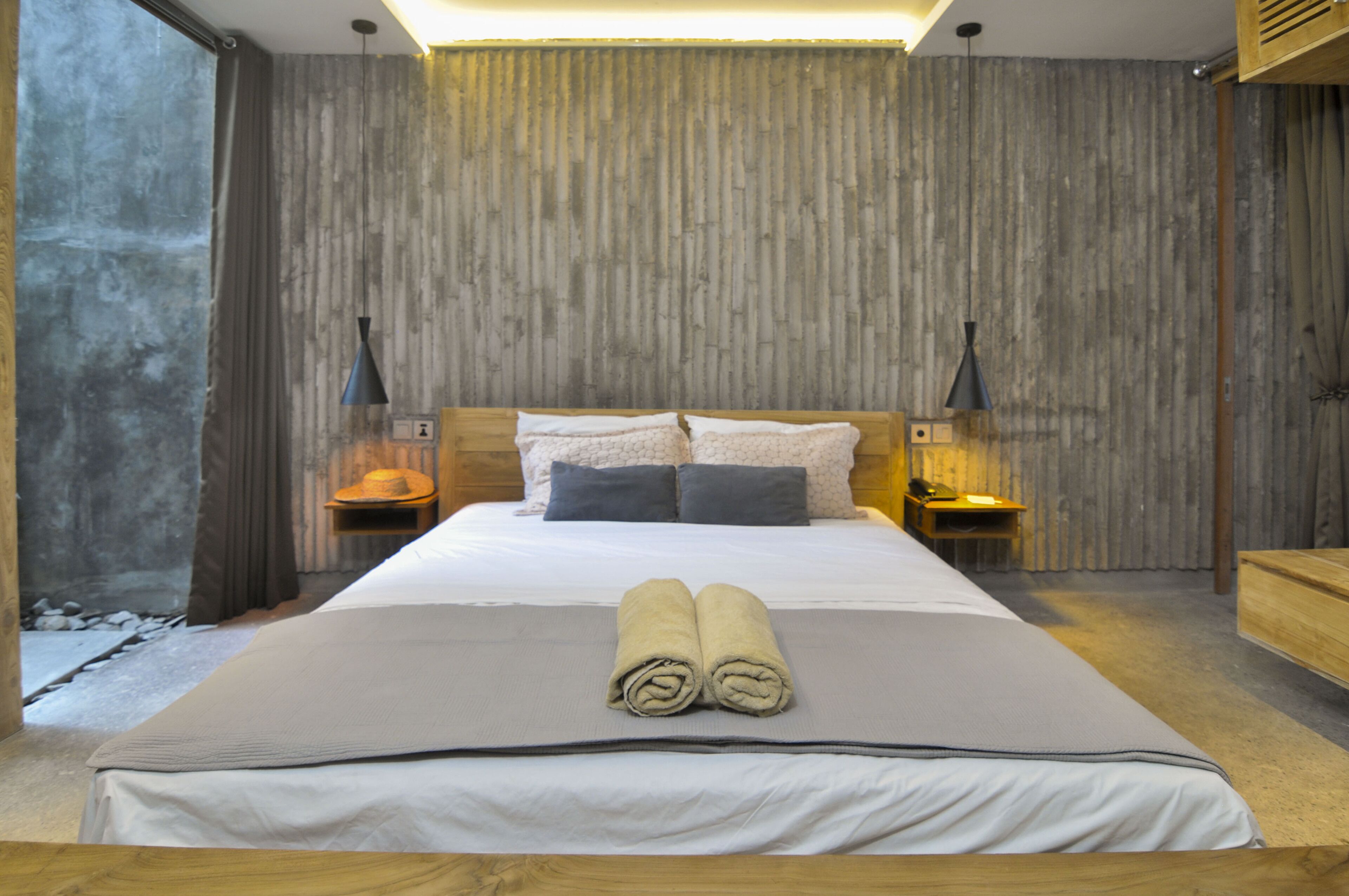 Een moderne slaapkamer met een groot bed, een houten hoofdbord en twee nachtkastjes met lampen.