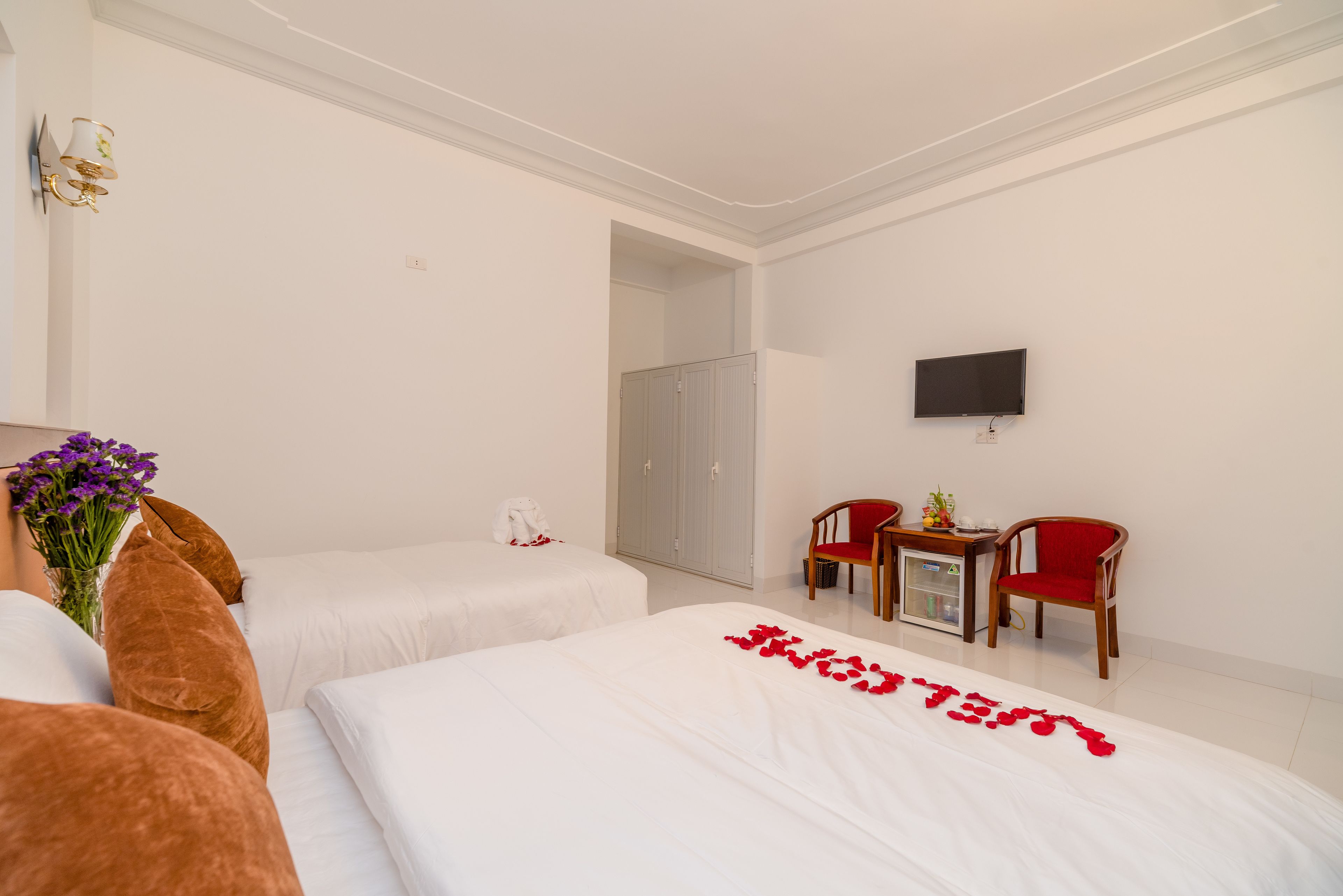 A hotel room with two beds, a TV, a desk with chairs, and a wardrobe.
