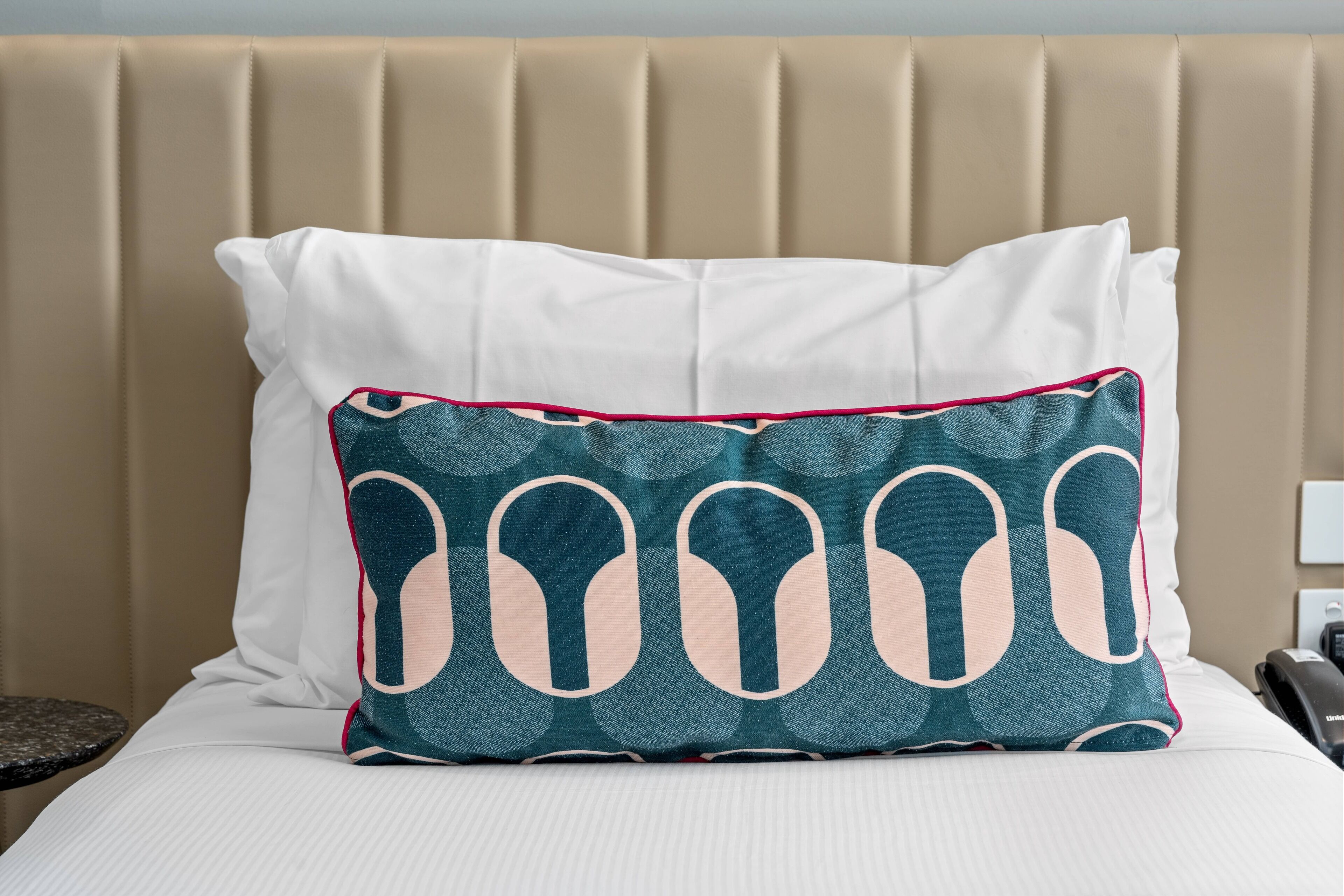 A bed with a beige headboard and a white pillow.