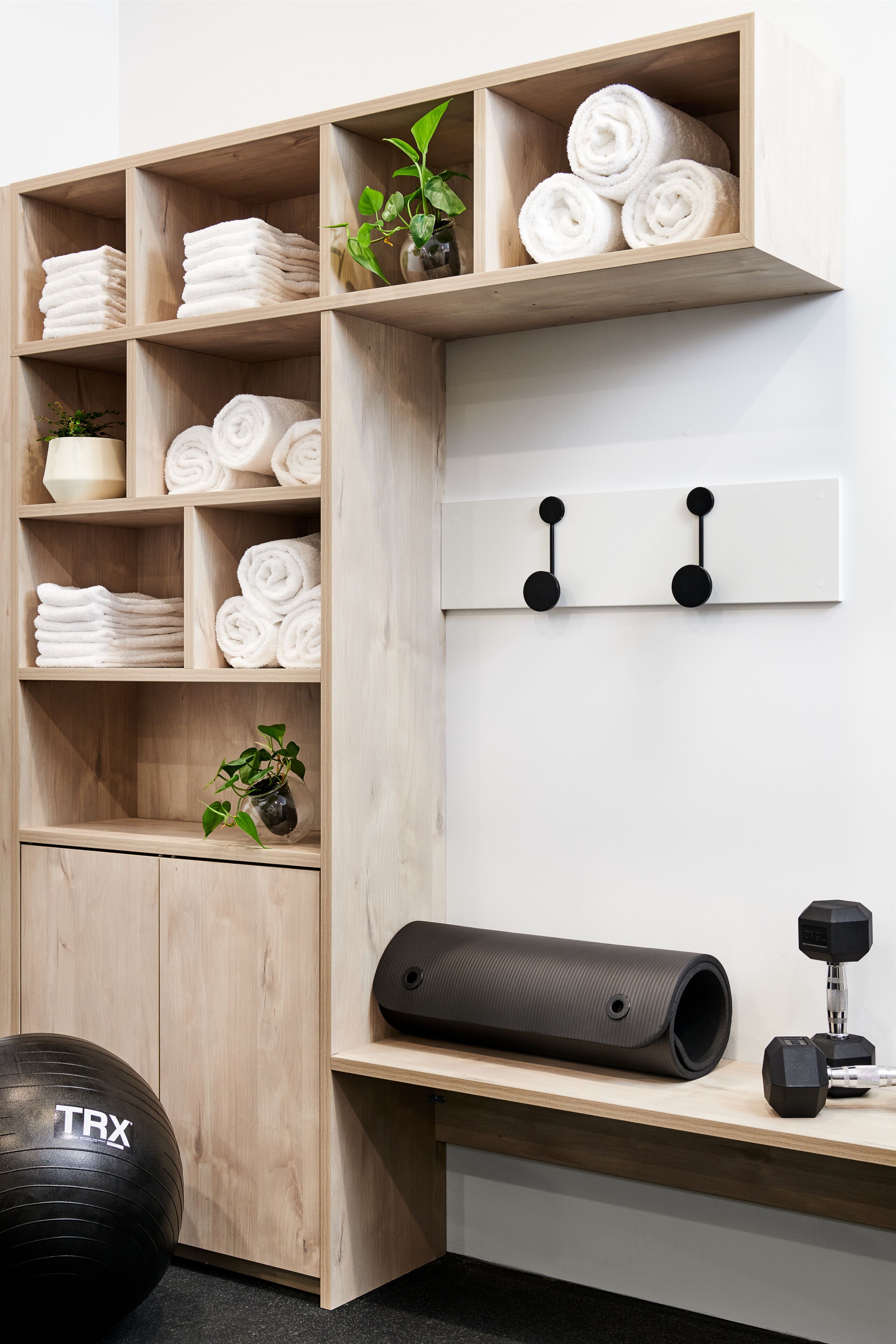 A neatly organized storage unit with shelves holding folded towels and potted plants.