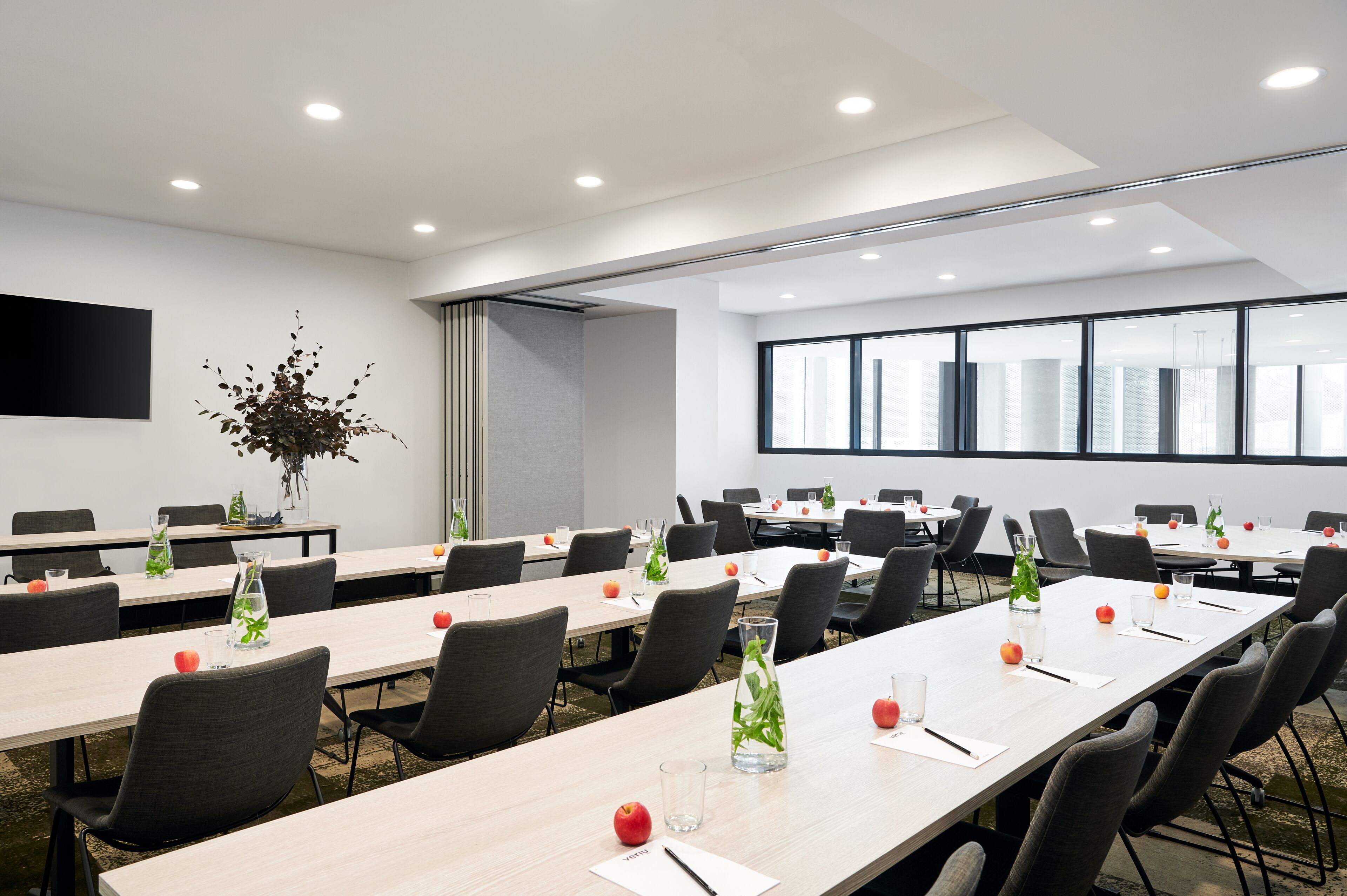 Une salle de conférence avec de longues tables, des chaises et une grande fenêtre.