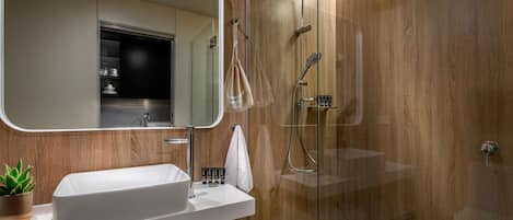 A modern bathroom with a large mirror, a white sink, and a glass-enclosed shower area.