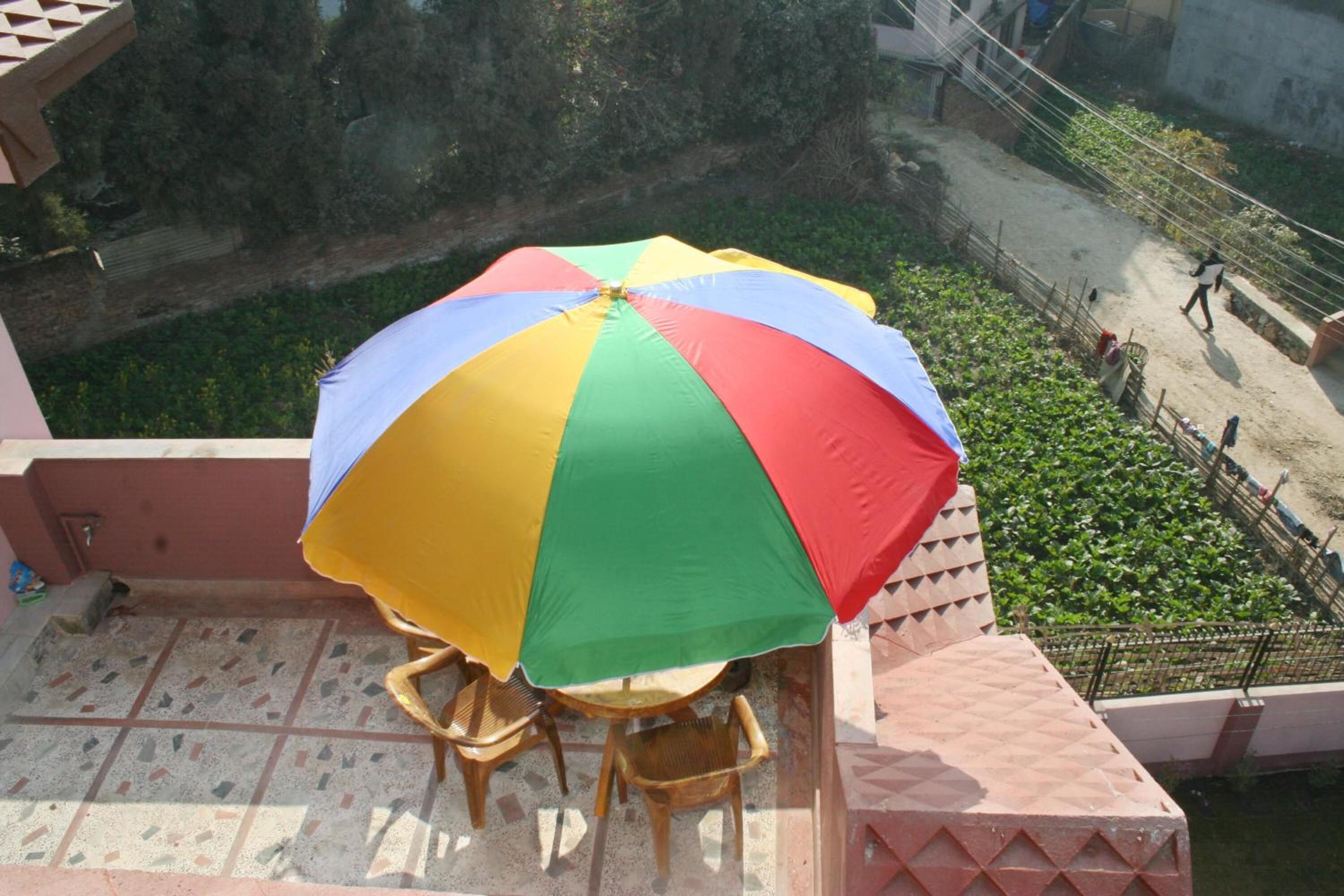 Varanda com um guarda-sol colorido, uma mesa e duas cadeiras.