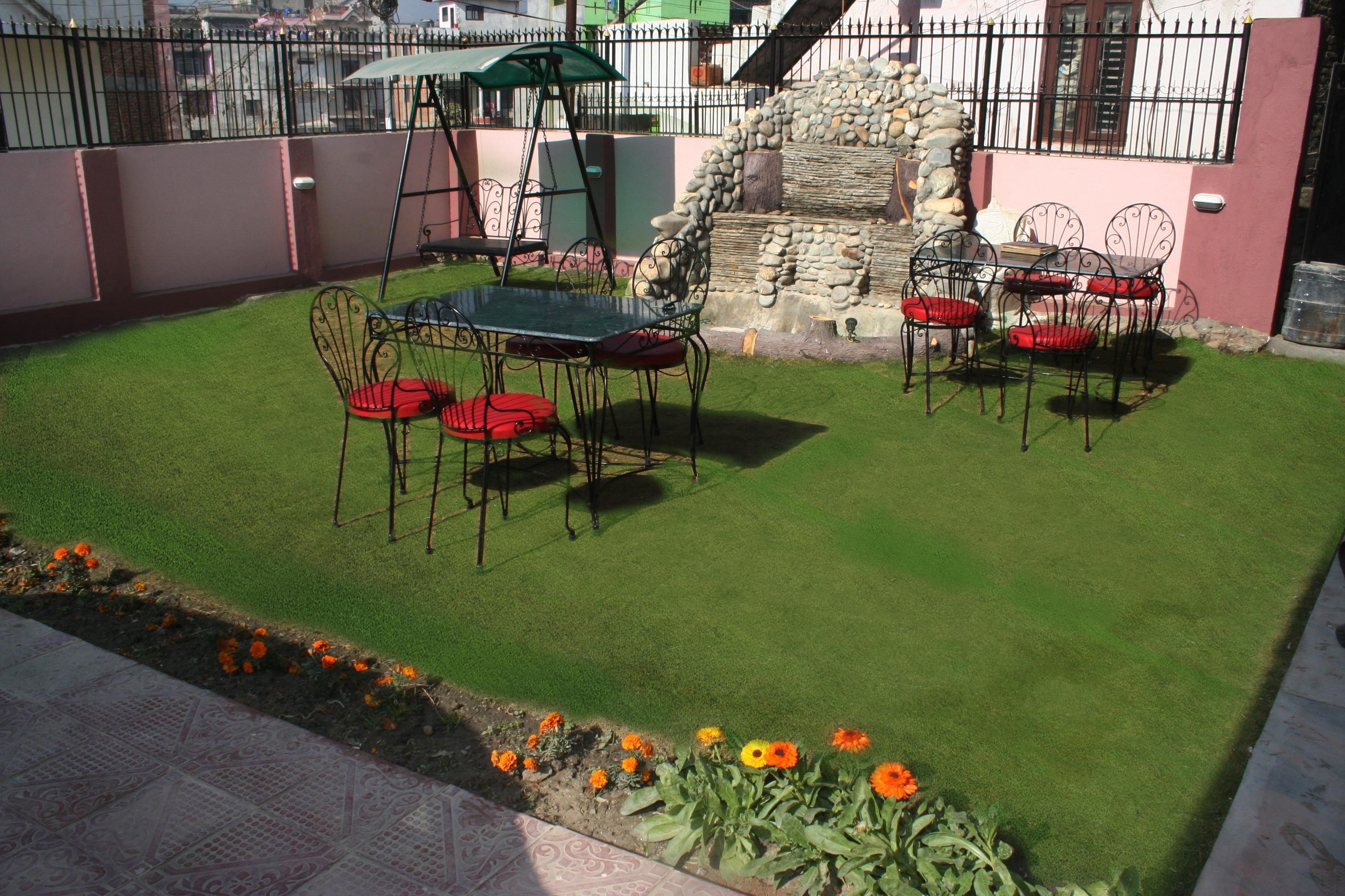 Une terrasse avec une table et des chaises, une balançoire et un mur en pierre.