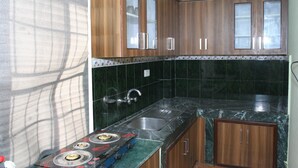 A kitchen with wooden cabinets, a stainless steel sink, and a gas stove. - Sitapaila Homestay and Apartment (Nagarjun)
