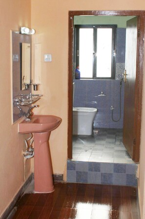 Un baño con lavamanos rosa, inodoro y zona de ducha.