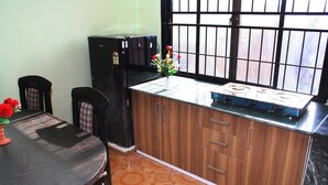 A kitchen with a stove, cabinets, and a window with bars. - Sitapaila Homestay and Apartment (Nagarjun)