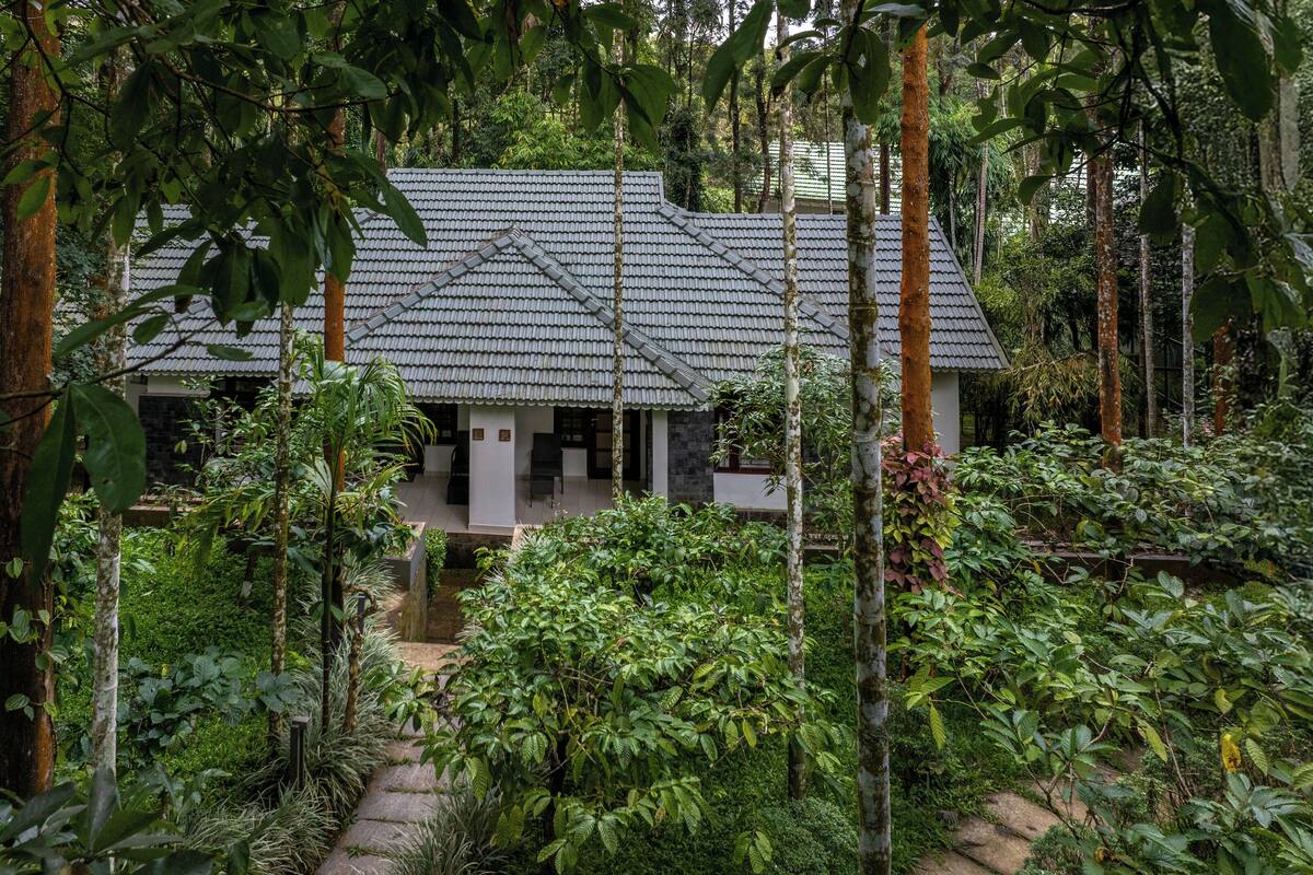 Una casa tradicional con tejado de baldosas, rodeada de densa vegetación tropical.