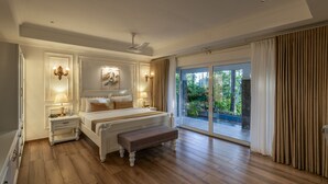 A spacious bedroom with a large bed, a bench, a nightstand, and a view of the outdoors through a sliding glass door. - The Woods Resorts Wayanad (Sulthan Bathery)