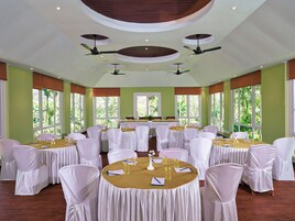 A conference room with round tables, white chairs, and ceiling fans.
