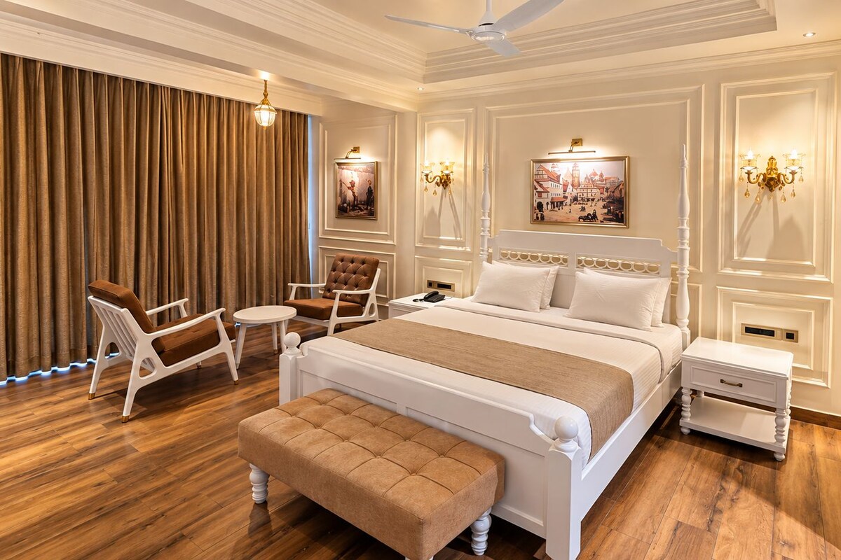 A bedroom with a large bed, a bedside table, a chair, a bench, and a wardrobe.