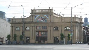 A historic building with a central entrance, large windows, and a decorative mural above the entrance. - Arden Motel (North Melbourne)
