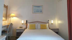 A hotel room with a bed, a desk, a chair, and a nightstand. - Arden Motel (North Melbourne)