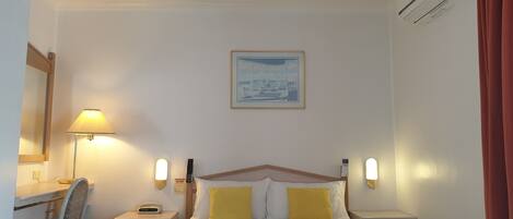 Una habitación de hotel con una cama, un escritorio, una silla y una mesita de noche.