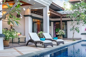 A poolside area with lounge chairs and potted plants. - Jewels Villas Phuket (Si Sunthon)