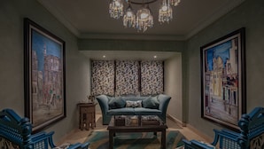 A living room with a blue sofa, a coffee table, and patterned wallpaper. - Le Riad Hotel de Charme (Cairo)