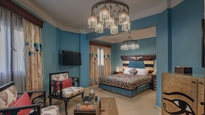 A bedroom with a bed, a chair, a desk, a television, and a cabinet. - Le Riad Hotel de Charme (Cairo)