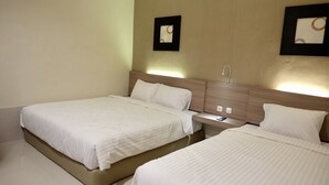 A hotel room with two beds, a bedside table with a lamp, and a wall-mounted picture. - Style50 homestay (Surabaya)