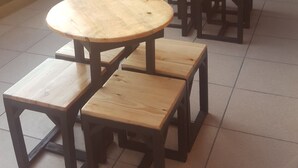 A set of wooden tables and benches arranged indoors with a view of greenery outside. - Style50 homestay (Surabaya)