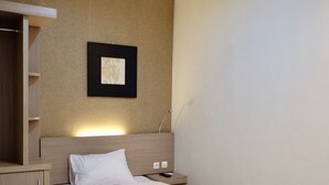 A hotel room with a bed, a nightstand, a wardrobe, and a framed picture on the wall. - Style50 homestay (Surabaya)