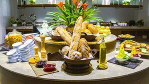 Buffet com diversos alimentos e um arranjo de pães.