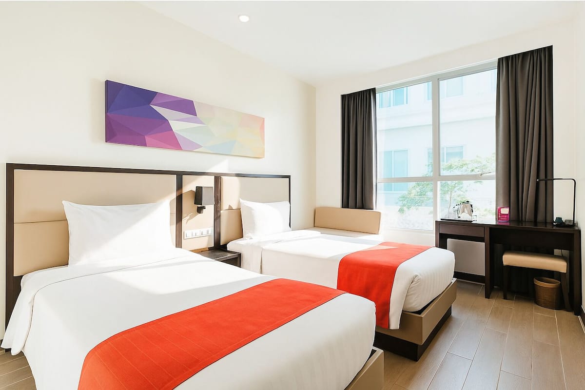 A hotel room with two beds, a desk, a chair, and a large window with curtains.