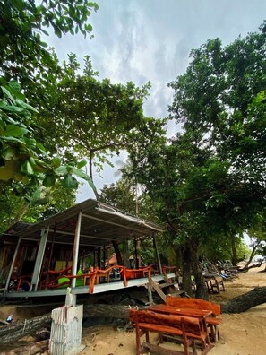 A rustic wooden structure with a covered porch, surrounded by lush greenery and trees.