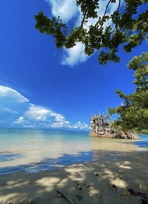 A beach with clear turquoise water, a sandy shore, and a small island with a structure made of wood and metal. - Koh Phu Valley (Nuea Khlong)