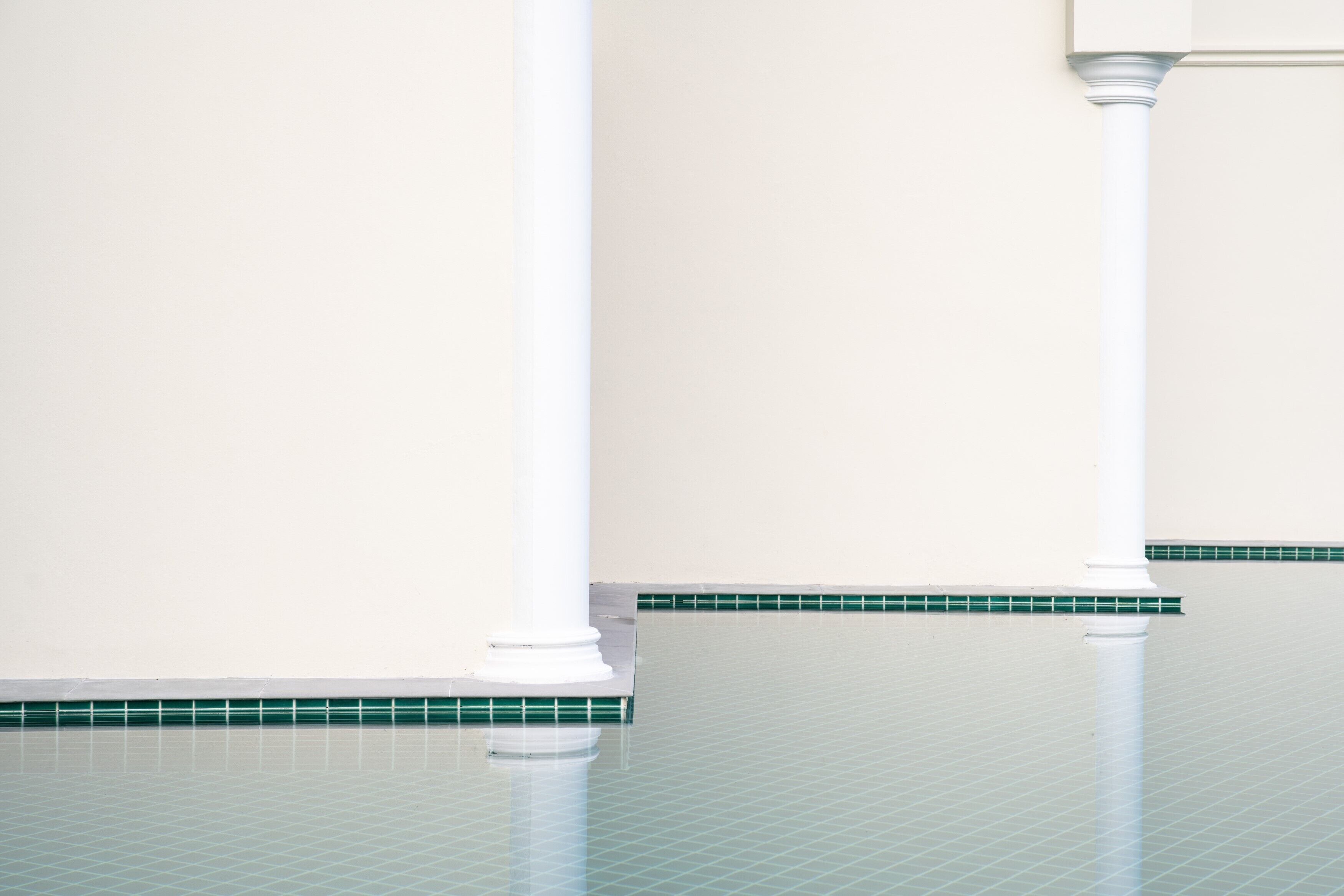 A clean, empty room with white columns and a tiled floor.