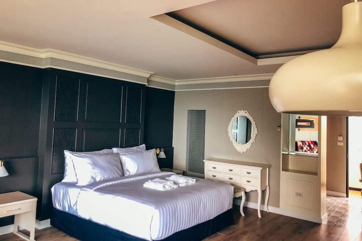 Un dormitorio con cama, mesitas de noche, cómoda, espejo y armario.