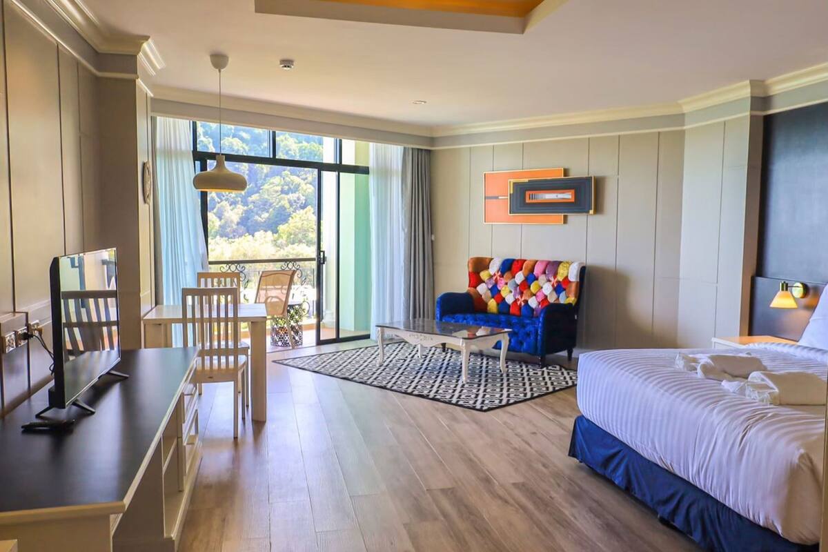Una habitación de hotel con cama, escritorio, silla, sofá y balcón con vistas.