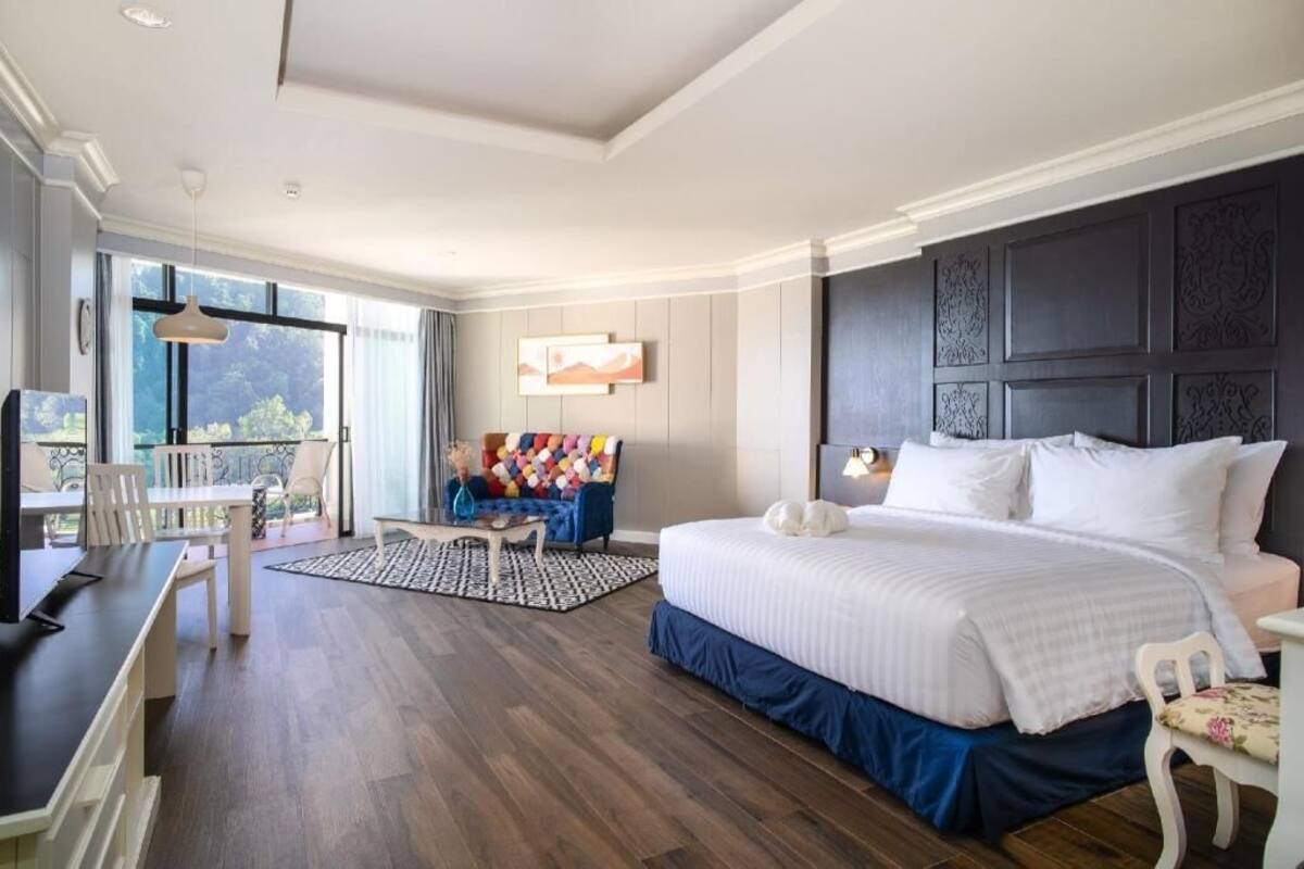 Habitación de hotel con una cama grande, un escritorio, una silla, un sofá y vistas al exterior.