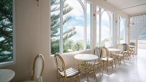 A room with large arched windows, wicker chairs, and a round table. - Heaven View Krabi (Krabi)