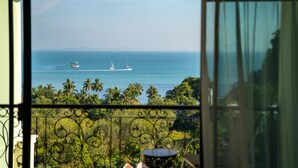 A view through a window of a balcony overlooking a body of water with boats, palm trees, and a distant shoreline. - Heaven View Krabi (Krabi)