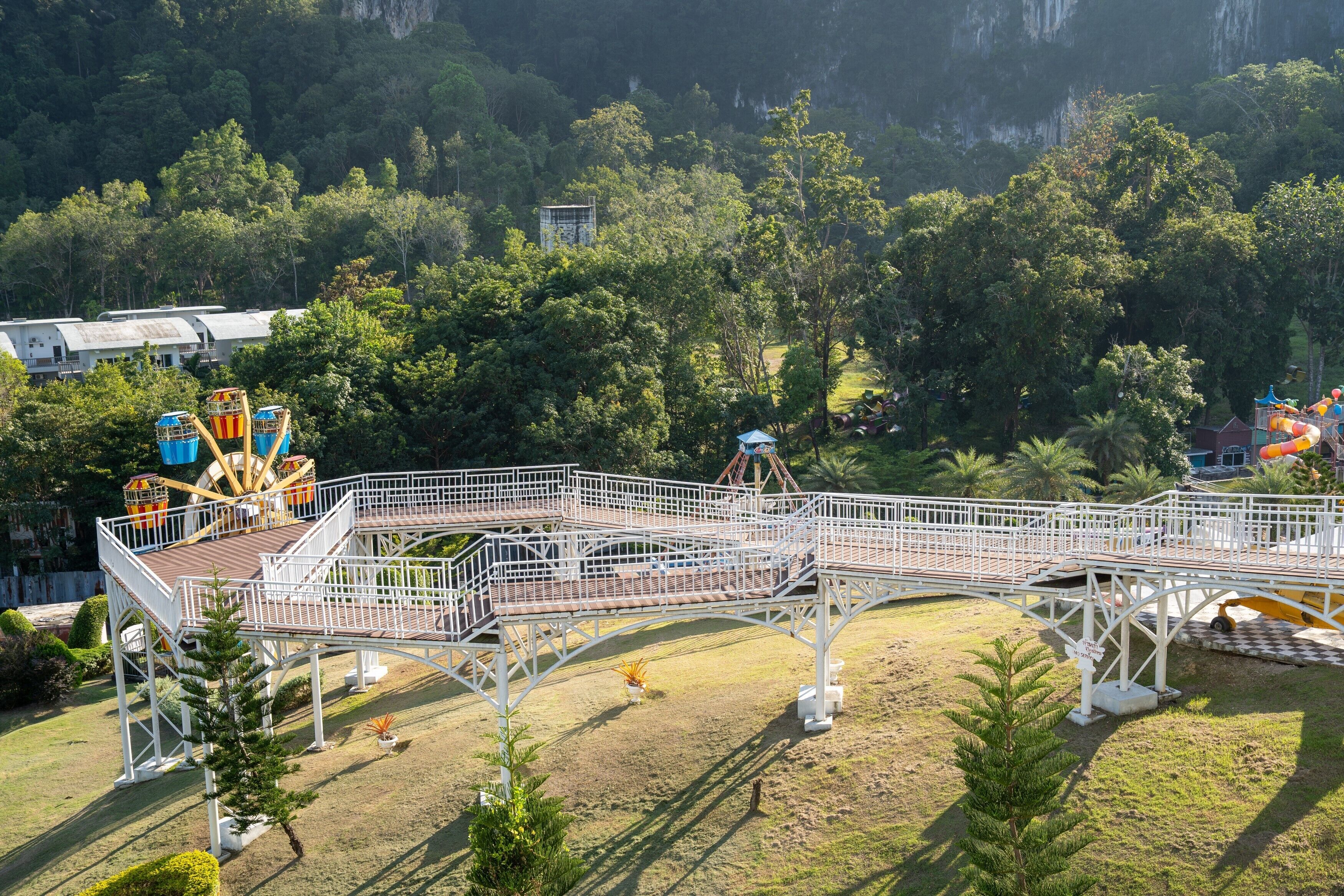 Un parco a tema con una montagna russa, una ruota panoramica e una struttura a ponte.