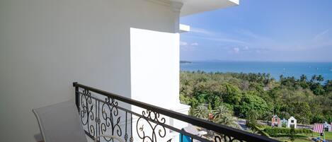A balcony with a view of the sea and greenery.