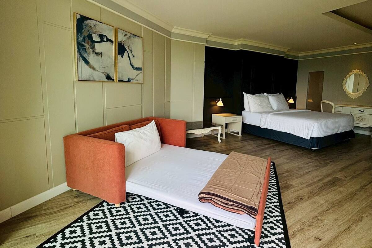 Una habitación de hotel con cama, sofá, una mesita y una lámpara.