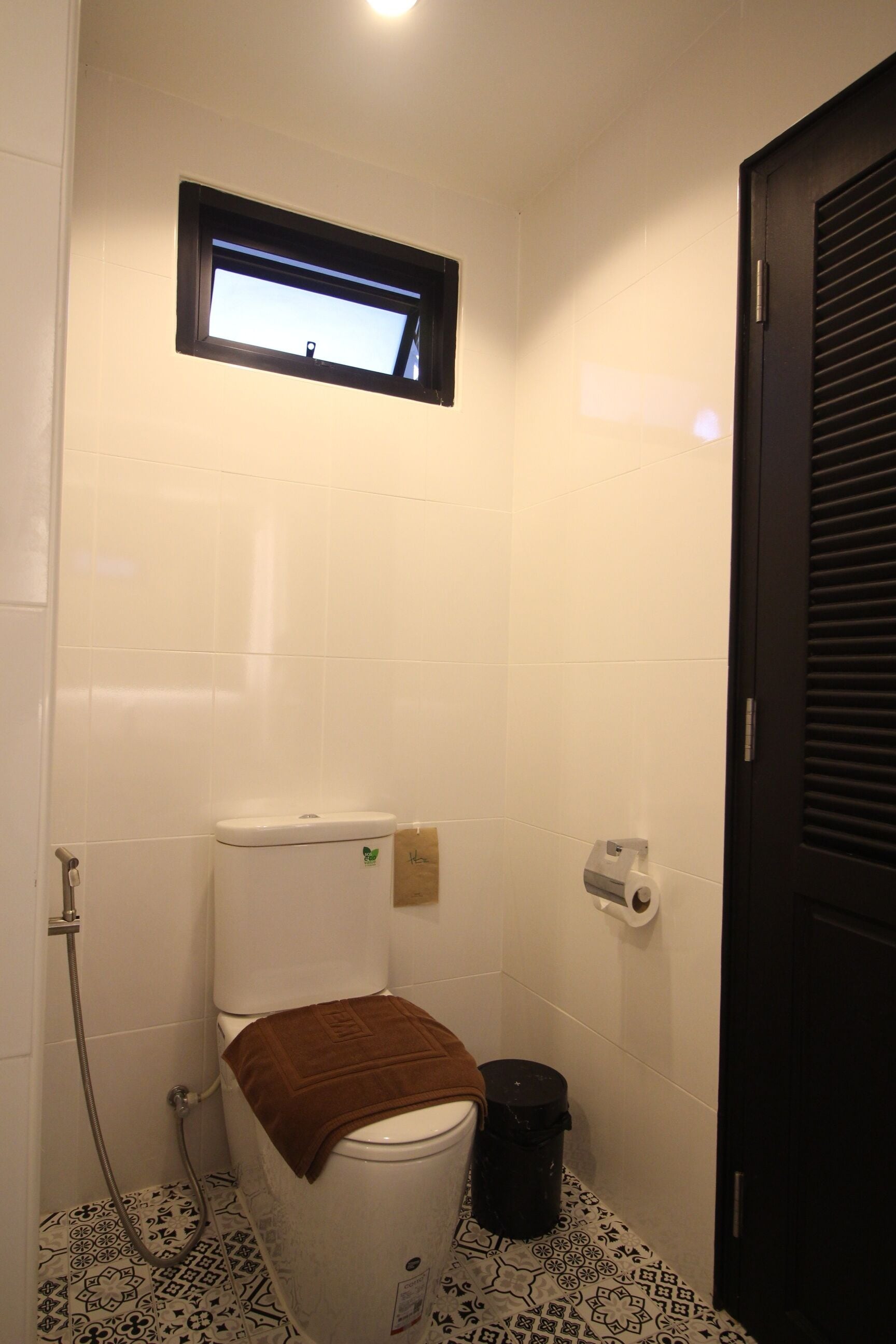 Un baño pequeño y funcional con inodoro, ducha y ventana.