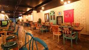 A restaurant with multiple tables and chairs, a brick wall, and hanging lights. - Brilliant Hotel & Convention Center (Indore)